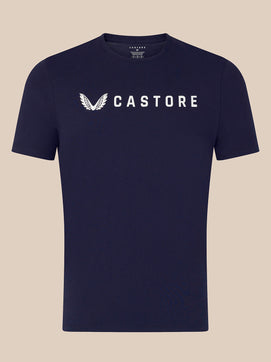 A navy blue short-sleeve crewneck t-shirt with a white Castore wing logo and brand name printed across the chest, displayed against a solid beige background.